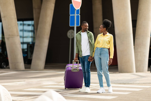 Reizen. Afro-Amerikaanse echtgenoten staan met koffer Reizen op vakantie poseren in de buurt van de luchthaven Terminal buiten. Volledige lengte schot van reizigers paar. Toerisme en vervoer Concept - Foto, afbeelding