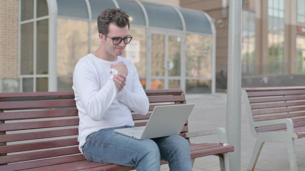 Casual Man with Wrist Pain Using Laptop while Sitting on Bench - Photo, Image