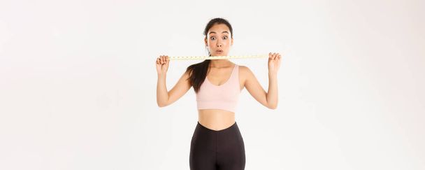 Fitness, sağlıklı yaşam tarzı ve refah konsepti. Etkilenmiş ve mutlu Asyalı bayan sporcu bel üstüne bant gösteriyor ve egzersiz programıyla kilo veriyor, spor salonuna gidiyor.. - Fotoğraf, Görsel