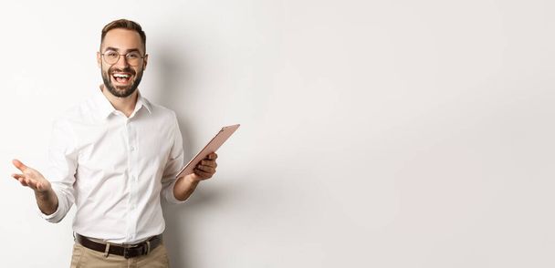 Satisfied businessman praising good work, reading report on digital tablet, standing happy against white background. - Φωτογραφία, εικόνα