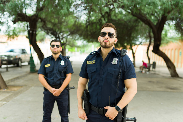 Portré két rendőrről, akik partnerként dolgoznak, és a városi parkban álló bűnüldöző szervek tagjai. - Fotó, kép