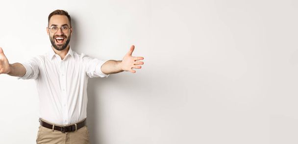 Happy man stretching hands in warm welcome, waiting for hug or greeting someone, standing over white background. - Fotoğraf, Görsel