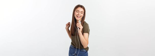 Портрет веселой милой женщины, слушающей музыку в наушниках и танцующей на белом фоне
 - Фото, изображение