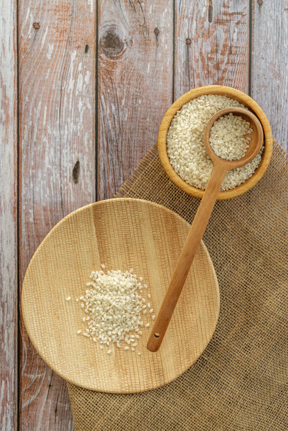 Rice in cereal on a wooden plate and a bamboo wooden bowl on a light wooden table - Photo, Image