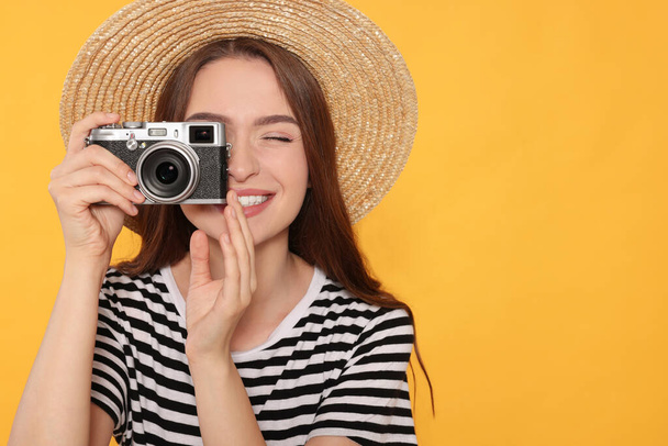 黄色の背景、テキストのためのスペースで写真を撮るカメラを持つ若い女性。面白い趣味 - 写真・画像