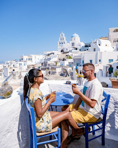 Im Urlaub in Santorin Griechenland besuchen zwei Männer und Frauen Oia Santorini mit weißgetünchten Gebäuden. Junges Paar beim Sonnenaufgang auf Santorin Griechenland - Foto, Bild