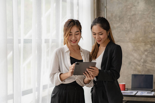 Két gyönyörű ázsiai nő konzultál egy kollaboratív struktúrával táblagépekkel, akik képernyőket néznek az online vásárláshoz. internetes együttműködési koncepció - Fotó, kép