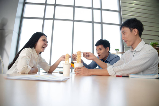 company employee have a cozy  lunch  break  with cup noodle together with smile  in meeting room - Photo, Image