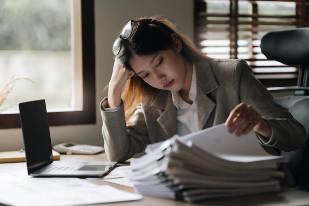 Stresszes ázsiai üzletasszony aggódni sok dokumentumot íróasztal az irodában. - Fotó, kép
