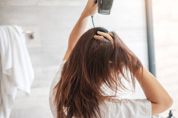 young woman using hair dryer at home or hotel. Hairstyles and lifestyle concepts - Foto, Imagem