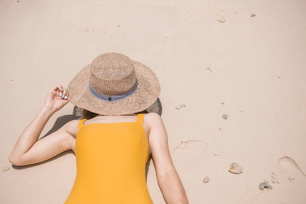 黄色の水着と帽子の女性観光客、島のパラダイスビーチで幸せな旅行者日光浴。目的地,さまよう欲望,アジア旅行,熱帯夏,休暇と休日の概念 - 写真・画像