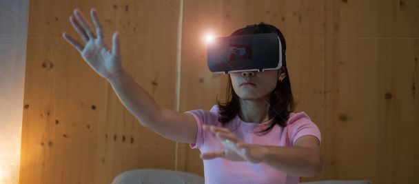 Młoda kobieta używająca gogli wirtualnej rzeczywistości w łóżku. VR, przyszła technologia cyfrowa, gra, rozrywka filmowa, metawersy, koncepcja NFT i 3D cyberprzestrzeni - Zdjęcie, obraz
