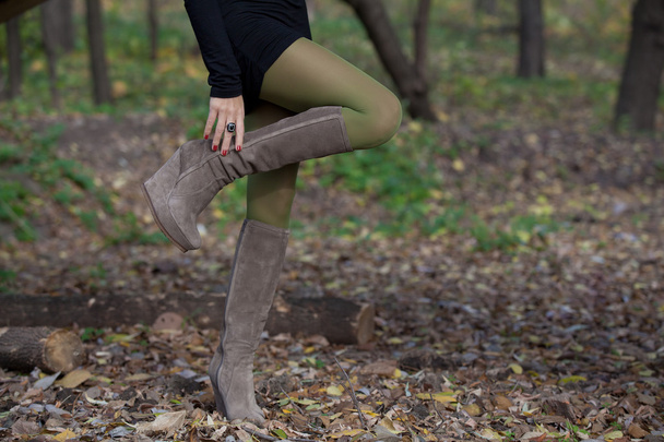 Beautiful woman legs in suede boots in autumn forest - Фото, зображення