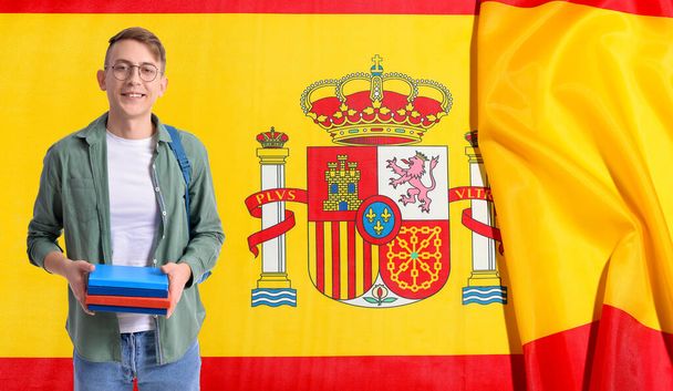 Студент с книгами против флага Испании. Концепция изучения испанского языка - Фото, изображение