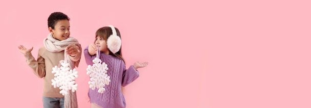 Lindos niños pequeños en suéteres de invierno y con copos de nieve sobre fondo rosa con espacio para el texto - Foto, Imagen
