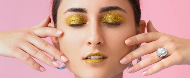 Attraktive junge Frau mit goldglänzendem Make-up auf rosa Hintergrund, Nahaufnahme - Foto, Bild