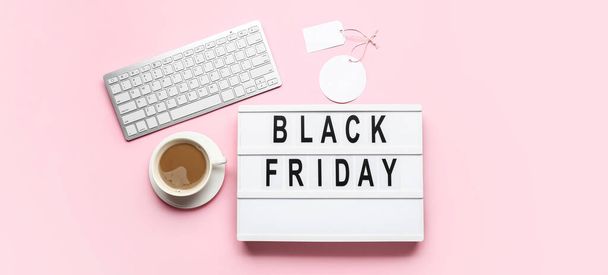 Board with text BLACK FRIDAY, cup of coffee and computer keyboard on pink background - Φωτογραφία, εικόνα