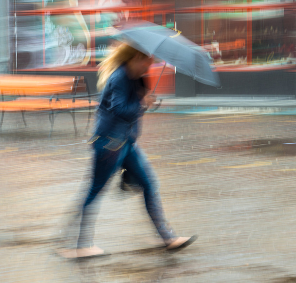 雨の日に道を歩いている女性 - 写真・画像