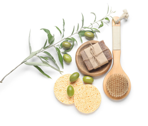 Composition with soap bar, massage brush, makeup sponges and green olives on white background - Photo, Image