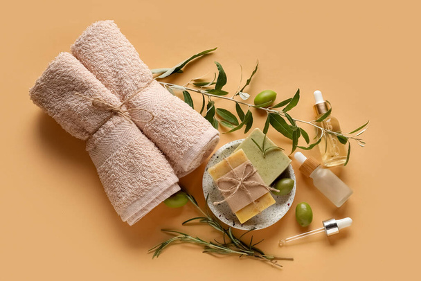 Composition with bottles of olive essential oil, soap bars and towels on color background - Photo, Image