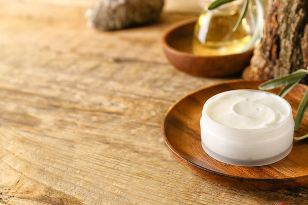 Plate with jar of natural olive cream on wooden table - Fotoğraf, Görsel