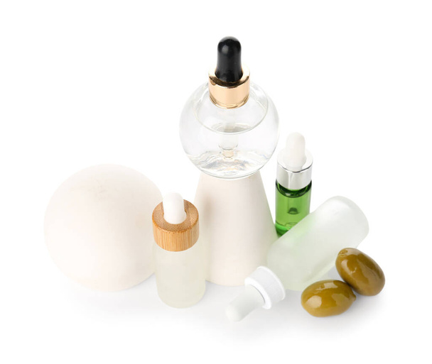 Koostumus valkoisella pohjalla olevien eteeristä oliiviöljyä sisältävien pullojen kanssa - Valokuva, kuva