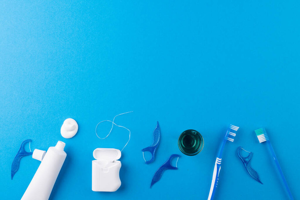 Image of toothbrush, toothpaste, string and liquid on blue surface. Health, dentistry, dental accessories and taking care of teeth concept. - Photo, image