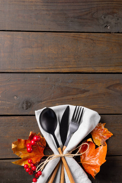 Overhead view of cutlery, rustic string napkin with autumn leaves, copy space on wooden background. Thanksgiving, autumn, fall, american tradition and celebration concept. - Foto, immagini