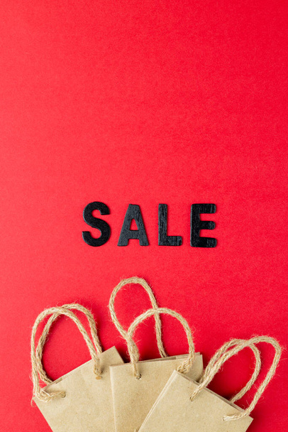 Composition of sale text and paper shopping bags on pink background. Retail, shopping and black friday concept. - Фото, зображення