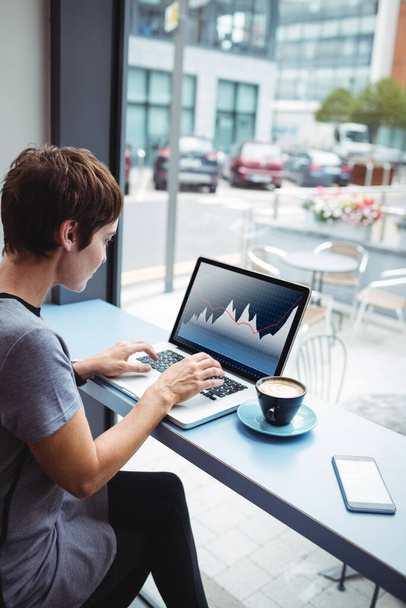 Businesswoman having a cup od coffee while using laptop in office - Photo, image