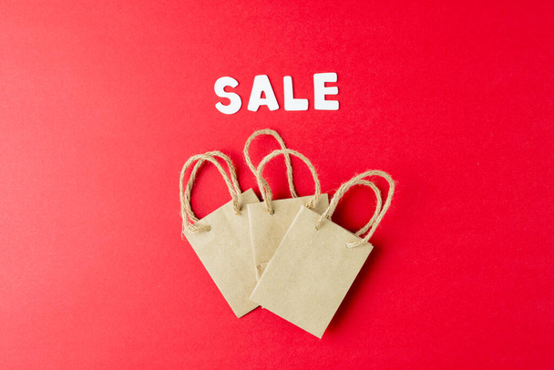 Composition of sale text and paper shopping bags on pink background. Retail, shopping and black friday concept. - Photo, Image