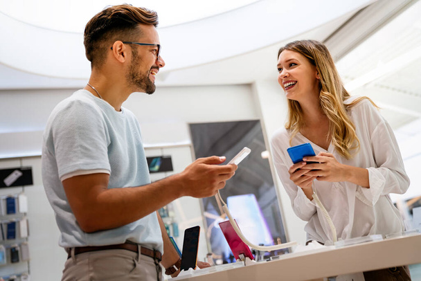 Happy young people shopping new smartphone in a store. People technology device new concept - Photo, image