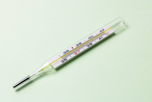 Mercury thermometer on table with green background. - Photo, Image