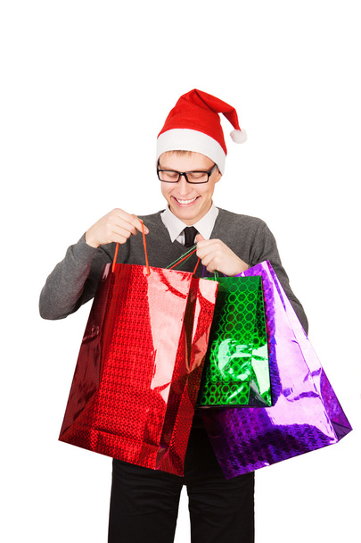 happy young attractive man wearing Santa hat holding shopping bags in Christmas sales - Foto, Imagen