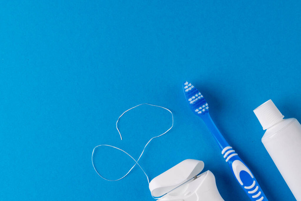 Image of toothbrush, toothpaste and dental string on blue surface. Health, dentistry, dental accessories and taking care of teeth concept. - Photo, image