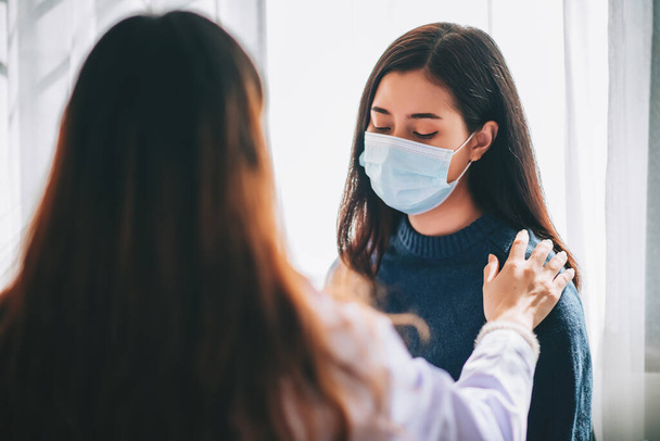 Ázsiai orvos meglátogatja és megvizsgálja a fiatal felnőtt nő a kórházban irodai szindróma és a depresszió. Az orvos ellenőrzi és konzultál az egészségügyi ellátás, visel maszkot, hogy megvédje covid-19 pandémia - Fotó, kép