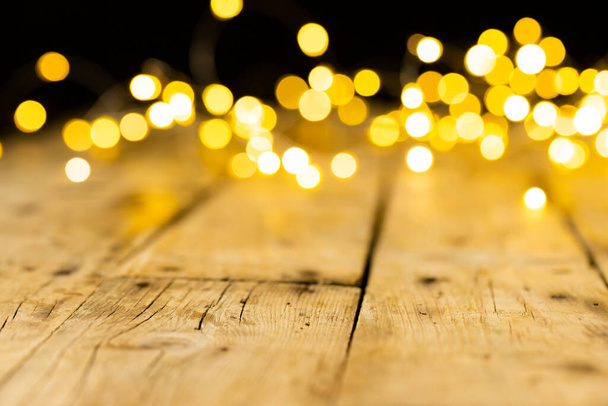Image of christmas out of focus fairy lights and copy space on wooden background. Christmas, tradition and celebration concept. - Foto, Bild