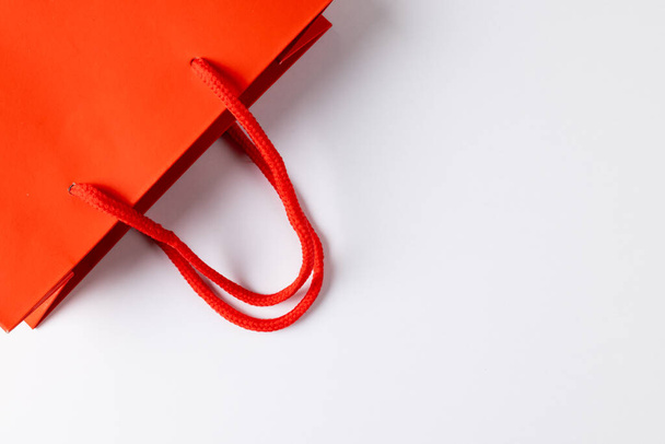 Composition of red paper shopping bag on white background. Retail, shopping and black friday concept. - Photo, image