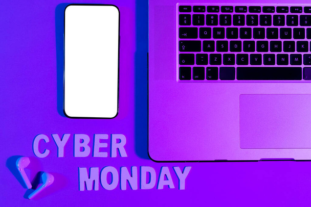 Image of cyber monday text, smartphone with copy space, laptop and earphones over neon purple. Retail, savings, online shopping, light and colour concept. - Foto, Imagen