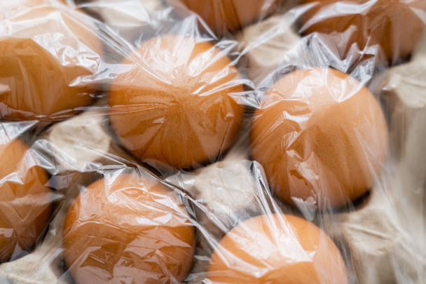 セロハン付き段ボール容器内の茶色の卵のトップビュー  - 写真・画像