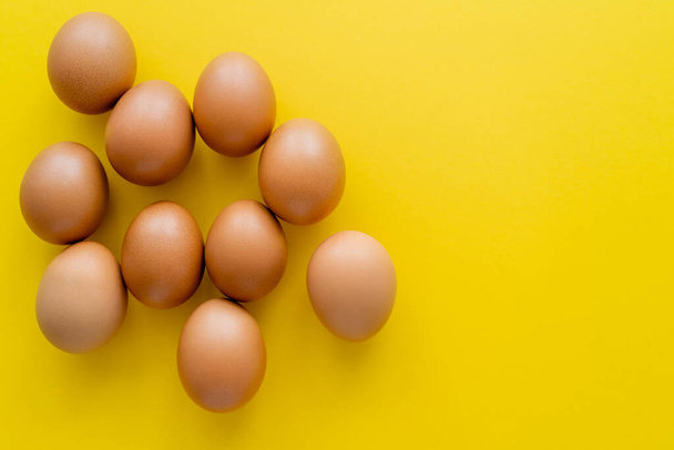 Top view of brown eggs on yellow background  - Fotó, kép