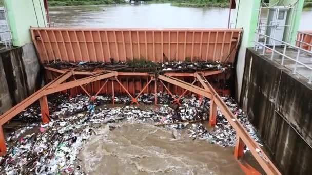 Aerial view of turbid brown forest water released by concrete dam drainage channels as water overflows in the rainy season with dry twigs and plastic waste at a dam gate in rural northern Thailand. - Footage, Video