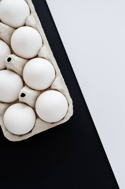 Vista dall'alto di uova di pollo fresche in contenitore di cartone su sfondo bianco e nero  - Foto, immagini