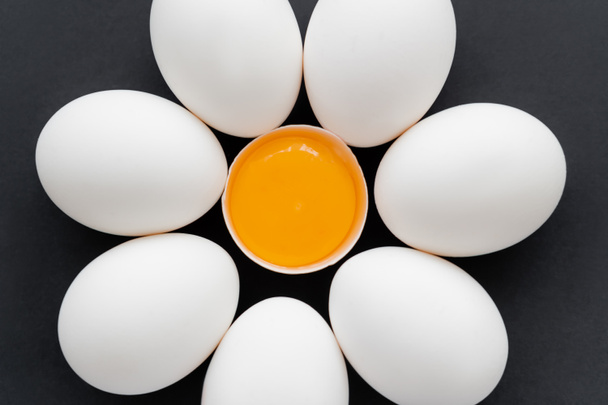 Puesta plana con huevos de pollo con yema en cáscara aislada sobre negro  - Foto, imagen