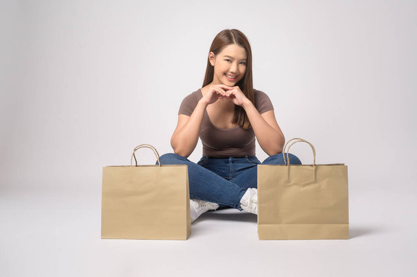 A Young asian woman holding shopping bag over white background studio, shopping and finance concept. - Zdjęcie, obraz