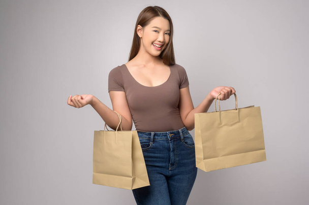 A Young asian woman holding shopping bag over white background studio, shopping and finance concept. - Foto, imagen