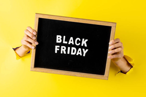 Composition of hands with black friday text on yellow background. Retail, shopping and black friday concept. - Fotografie, Obrázek