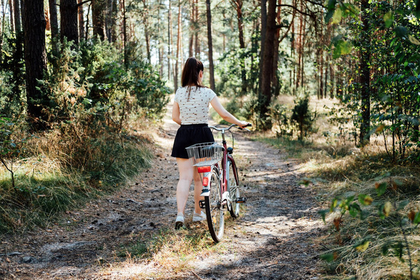 Bisikletçiliğin akıl sağlığı yararları, endişeleri azaltmak. Ormanda bisiklet sürmek. Forest Bycycle Patikası. Güneşli bir günde çam ormanında bisiklet süren bekar bir kadın. - Fotoğraf, Görsel