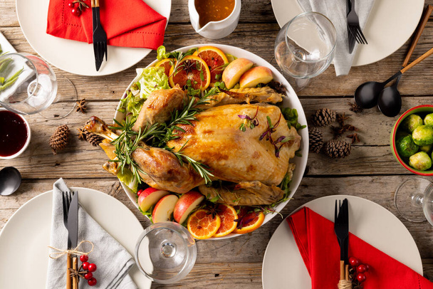 Overhead view of thanksgiving table with roast chicken and vegetables and autumn decoration on wood. Thanksgiving, autumn, fall, american tradition and celebration concept. - Foto, immagini
