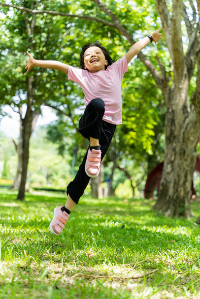 Portrait of child girl having fun jumping in the park outdoor. - Foto, afbeelding